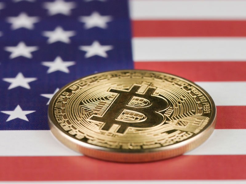 Picture of a crypto bitcoin laying atop a U.S. flag